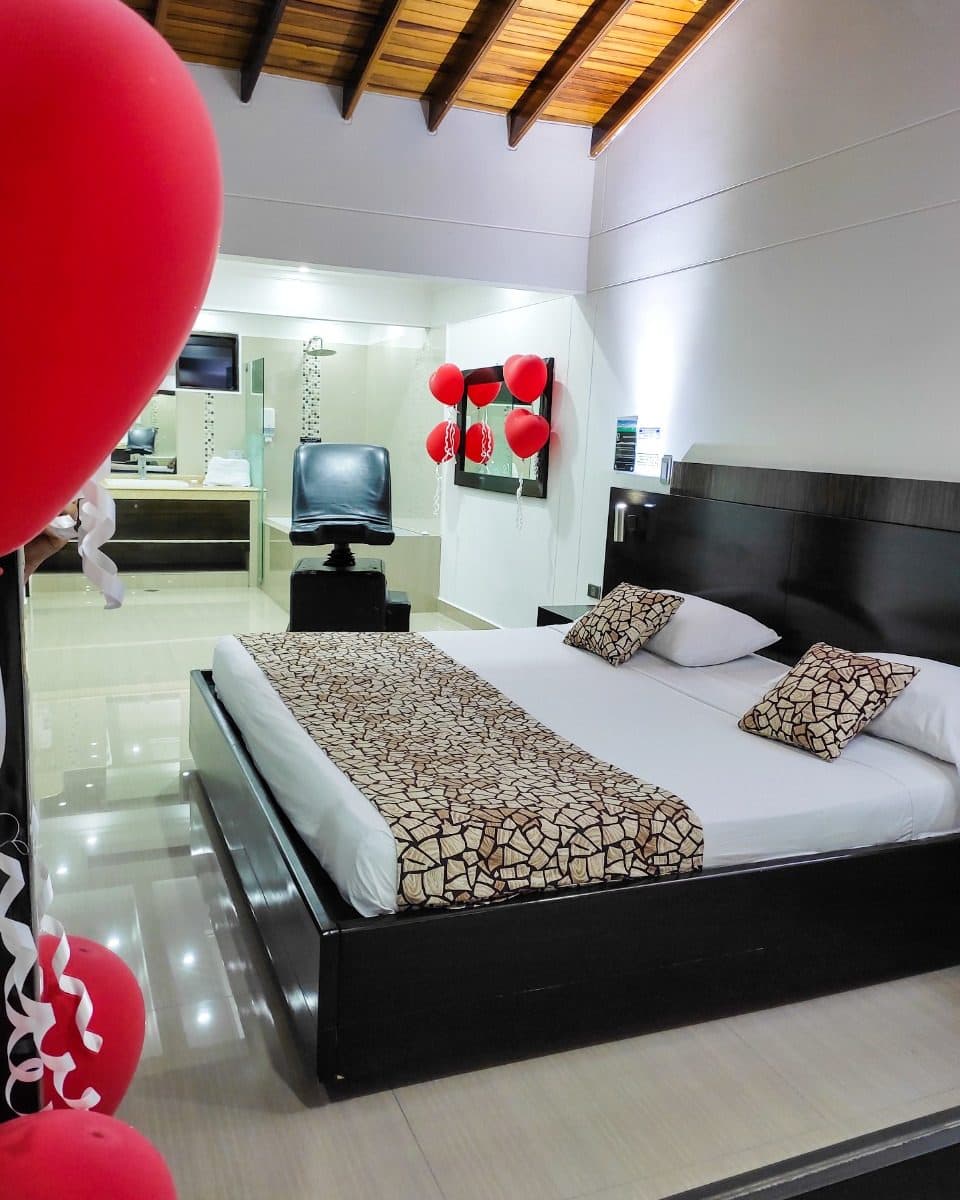 Suite Gold con decoración especial de ocasión: globos rojos en primer plano, la silla del amor y la ducha al fondo (no es la ambientación estándar)