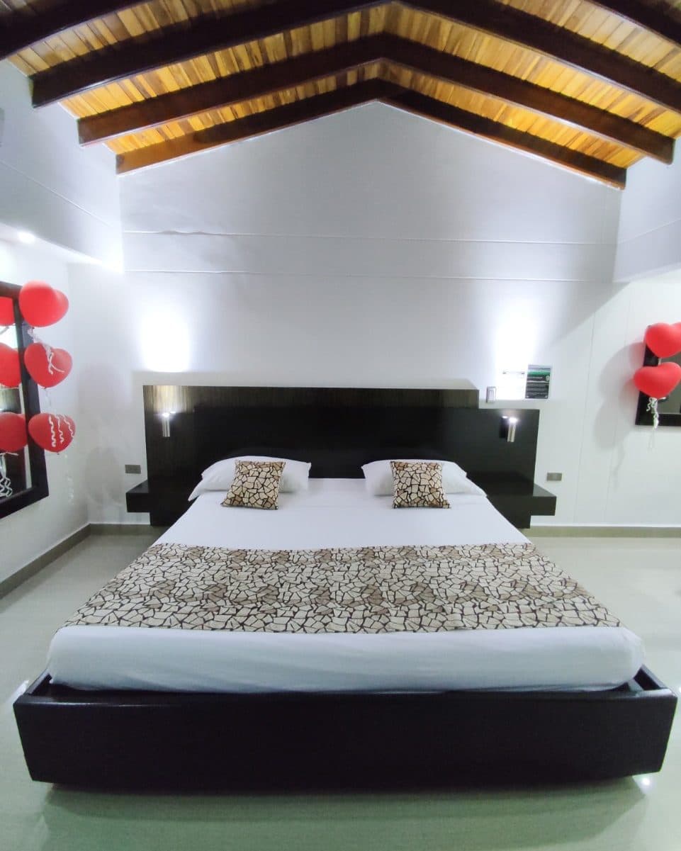 Suite Gold con decoración especial de ocasión: la cama de frente bajo el techo de vigas, con globos de corazón en los espejos de ambos lados (no es la ambientación estándar)