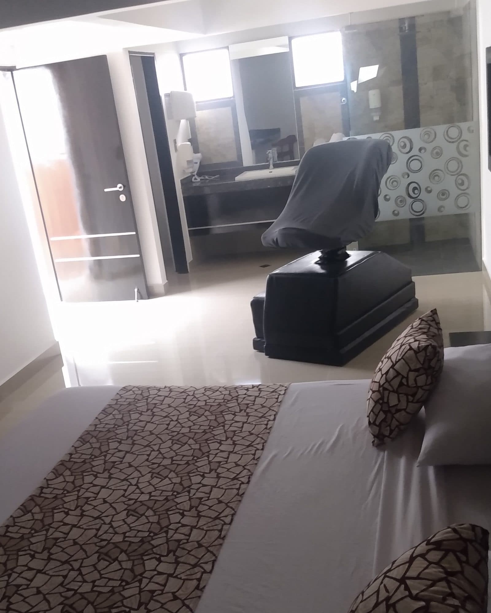Suite Silver: silla del amor frente al tocador con espejo y lavamanos, detrás de la mampara de vidrio