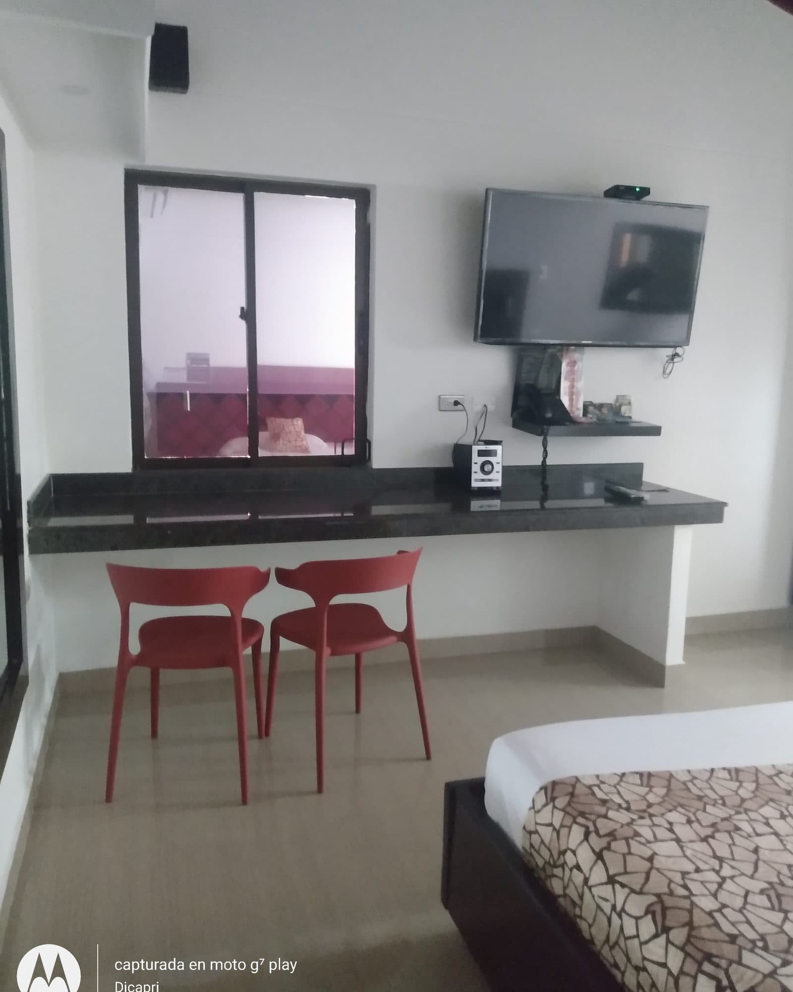 Suite Silver: barra de granito con dos sillas rojas y televisor en la pared, junto a la ventana interior