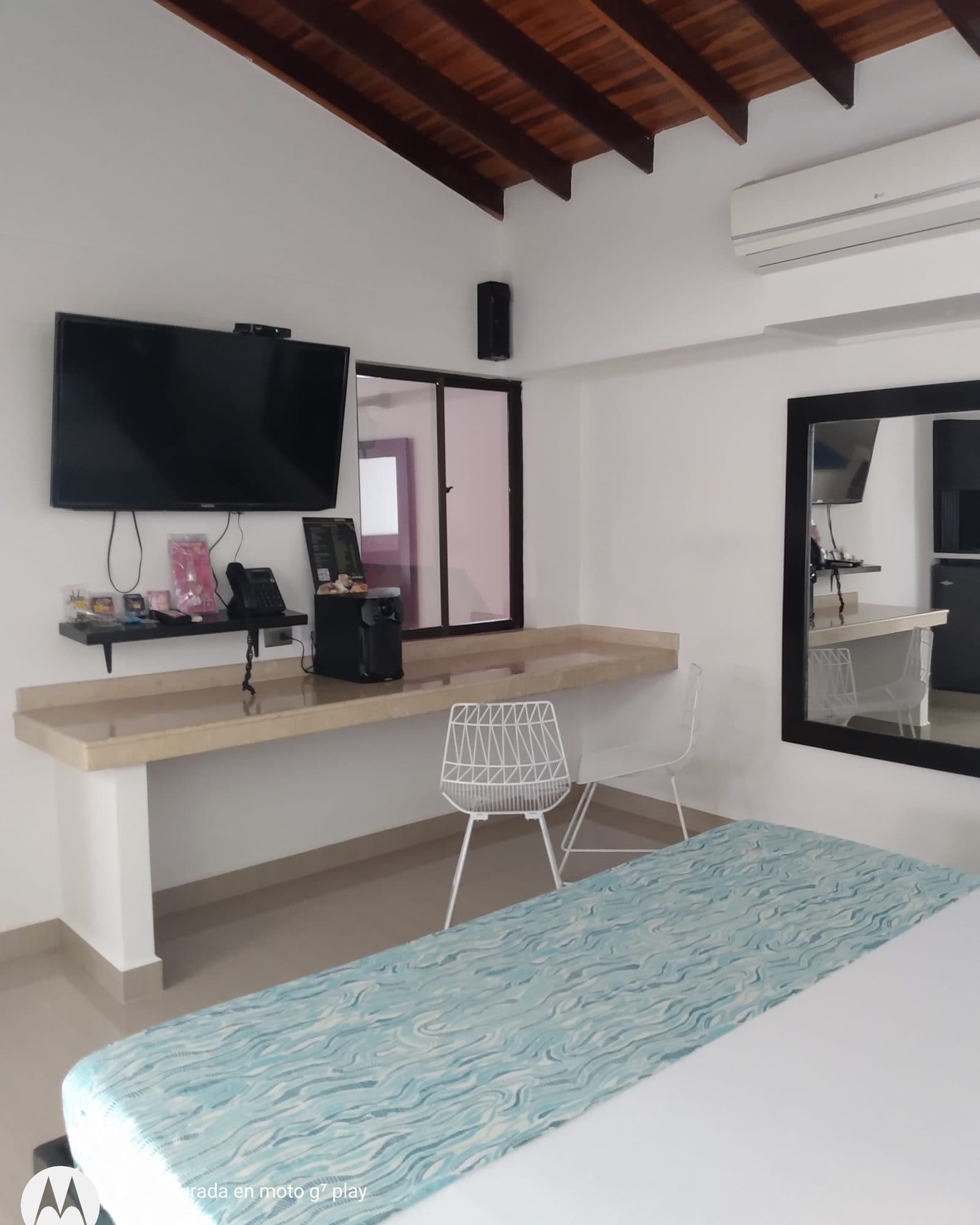 Suite Silver: techo de vigas de madera, mesa de mármol claro con dos sillas blancas y televisor, y aire acondicionado en la pared sobre el espejo