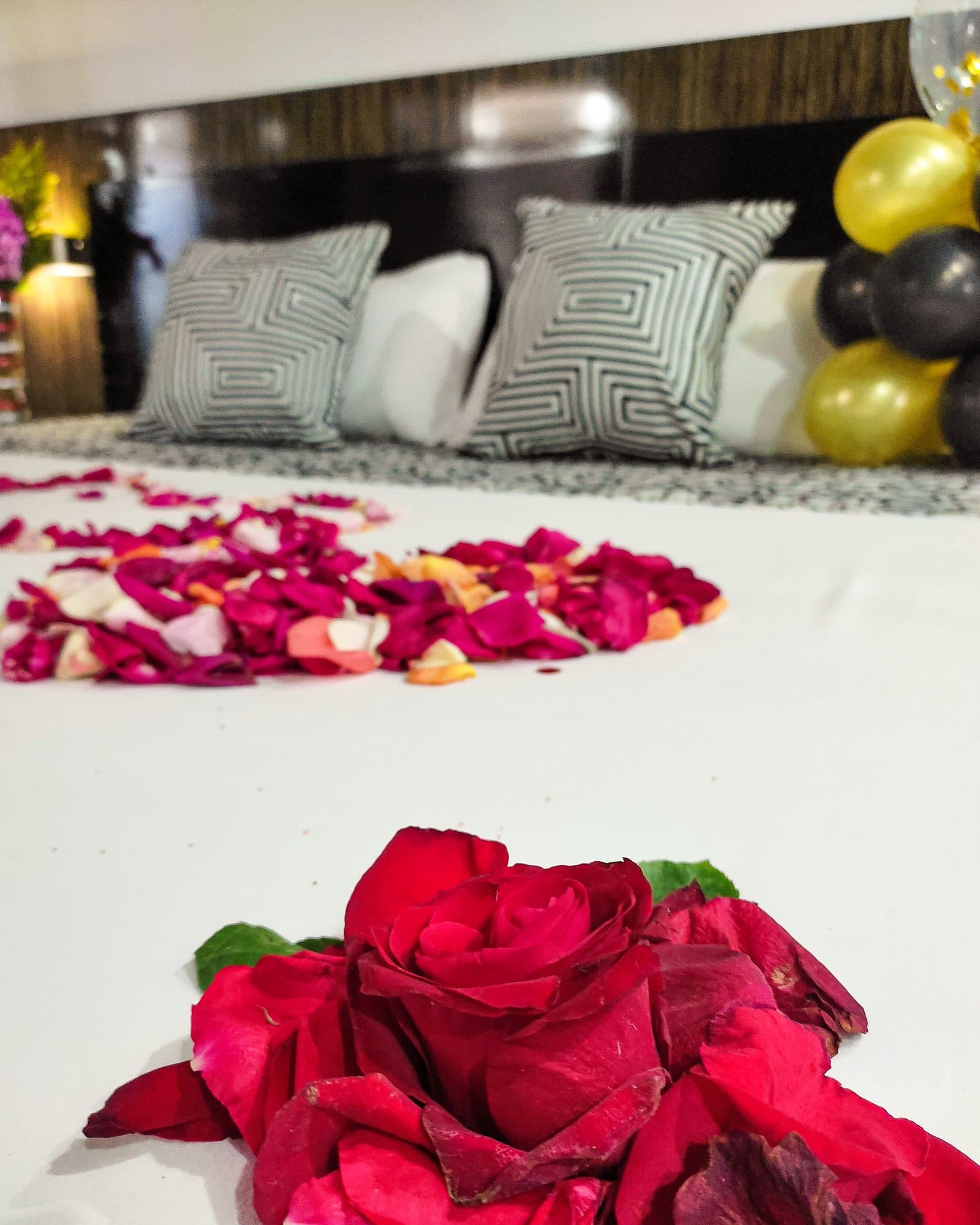 Suite Soho con decoración especial de ocasión: pétalos de rosa sobre la cama y globos negros y dorados de fondo (no es la ambientación estándar)