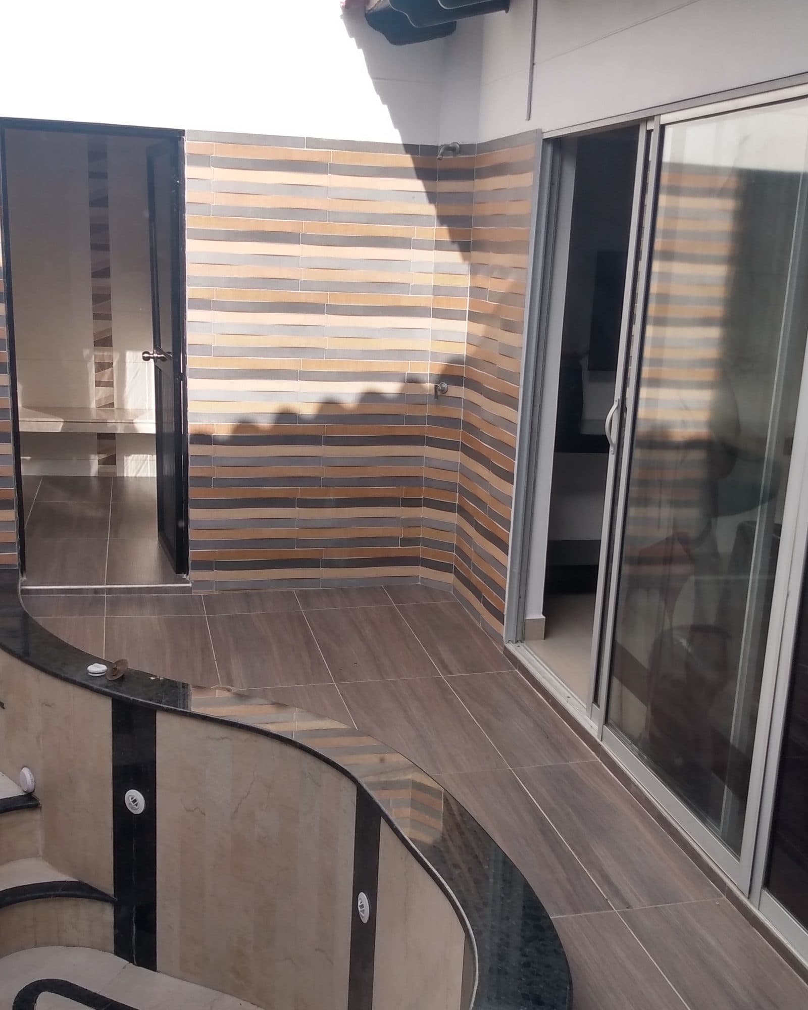 Suite Soho: patio interior de día, con el borde del jacuzzi, la pared de mosaico a rayas y la puerta corrediza de vidrio